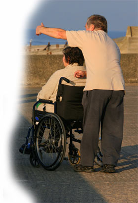 man pushing a woman in a wheelchair outside